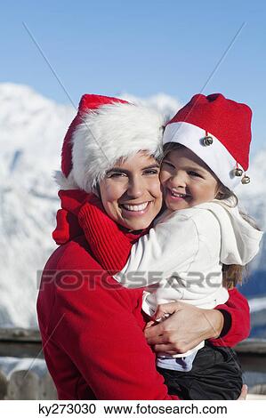 Mother and dauhter wearing Santa hats, hugging View Large Photo Image Stock Image - Mother and dauhter wearing Santa hats, hugging. Fotosearch