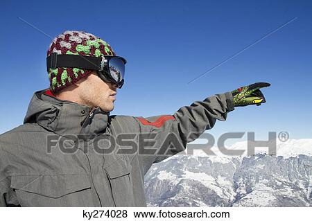 Portrait of young man in ski wear pointing View Large Photo Image Stock Photo - Portrait of young man in ski wear pointing. Fotosearch