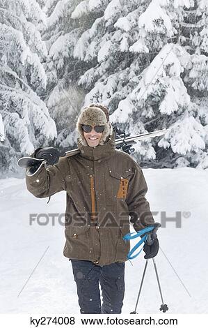 Stock Photo - Young man carrying skis on shoulders. Fotosearch