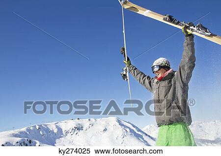 Young man holding his skis above his head View Large Photo Image Stock Photography - Young man holding his skis above his head. Fotosearch