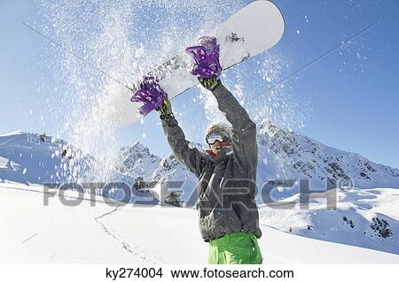 Young man holding his snowboard above his head View Large Photo Image Picture - Young man holding his snowboard above his head. Fotosearch