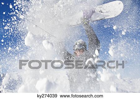 Stock Photo - Young man holding his snowboard above his head. Fotosearch