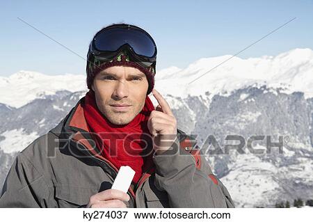 Young man in ski wear applying moisturizer on his face View Large Photo Image Stock Photo - Young man in ski wear applying moisturizer on his face. Fotosearch