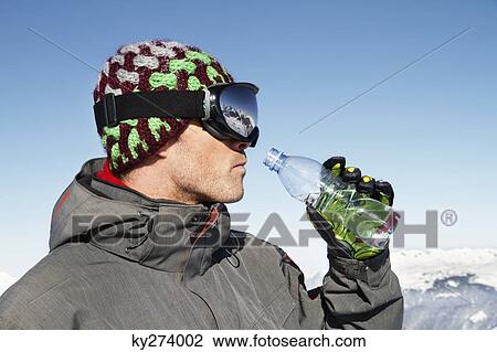 Young man in ski wear drinking water from a bottle, profile View Large Photo Image Stock Image - Young man in ski wear drinking water from a bottle, profile. Fotosearch