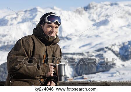 Young man in ski wear holding glass View Large Photo Image Stock Photograph - Young man in ski wear holding glass. Fotosearch