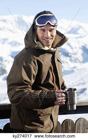 Young man in ski wear smiling at camera, holding glass View Large Photo Image Stock Photo - Young man in ski wear smiling at camera, holding glass. Fotosearch
