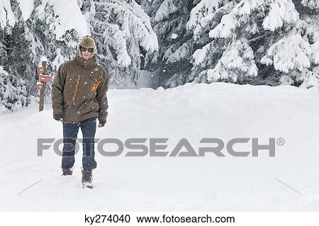 Stock Image - Young man walking in snow. Fotosearch