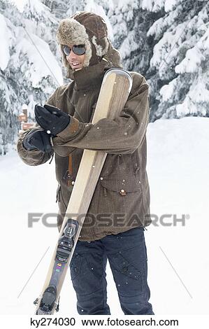 Young man with skis putting on his gloves View Large Photo Image Stock Image - Young man with skis putting on his gloves. Fotosearch