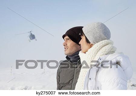 Young couple in winter clothes, helicopter in background View Large Photo Image Stock Photo - Young couple in winter clothes, helicopter in background. Fotosearch