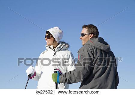 Stock Image - Young couple of skiers looking away. Fotosearch