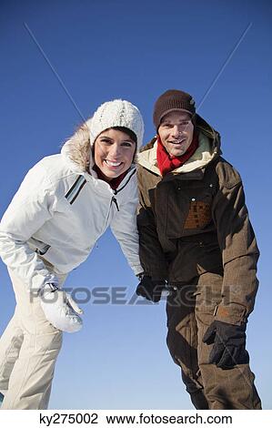 Young couple wearing ski wear, smiling at camera View Large Photo Image Stock Image - Young couple wearing ski wear, smiling at camera. Fotosearch