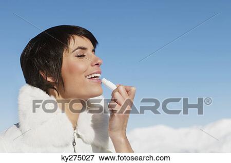 Young woman applying lip balm View Large Photo Image Stock Photo - Young woman applying lip balm. Fotosearch