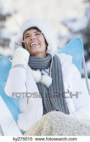Stock Photography - Young woman using mobile phone in snow. Fotosearch