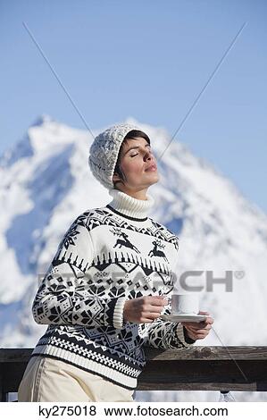 Young woman with coffee cup, enjoying winter sun, mountains in background View Large Photo Image Stock Photo - Young woman with coffee cup, enjoying winter sun, mountains in background. Fotosearch