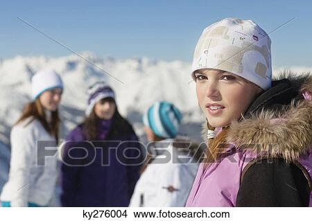 Teenage girl in ski clothes looking at camera, friends in background View Large Photo Image Picture - Teenage girl in ski clothes looking at camera, friends in background. Fotosearch