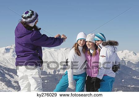Teenage girl photographing friends in snow View Large Photo Image Stock Photo - Teenage girl photographing friends in snow. Fotosearch