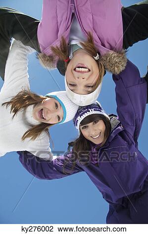 Stock Image - Three teenage girls in ski clothes, smiling at camera. Fotosearch
