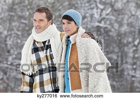 Stock Photograph - Young couple embracing, walking in snow. Fotosearch