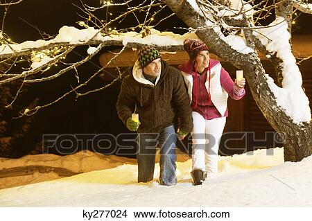 Young couple holding candles, walking in snow by night View Large Photo Image Picture - Young couple holding candles, walking in snow by night. Fotosearch