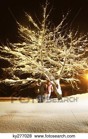 Stock Photo - Young couple holding candles, walking in snow by night. Fotosearch