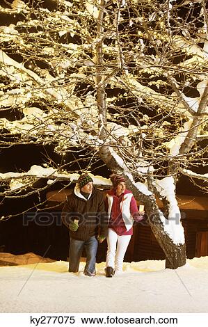 Stock Photography - Young couple holding candles, walking in snow by night. Fotosearch