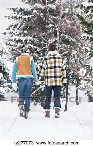 Young couple holding hands, walking in snow, rear view View Large Photo Image Stock Image - Young couple holding hands, walking in snow, rear view. Fotosearch