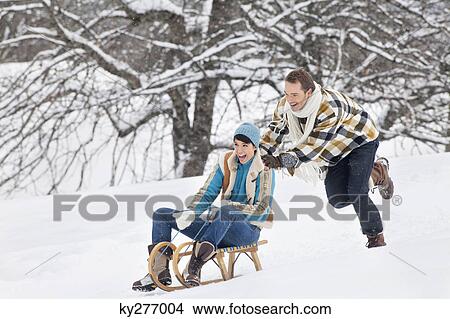 Young man pushing woman on sled View Large Photo Image Picture - Young man pushing woman on sled. Fotosearch
