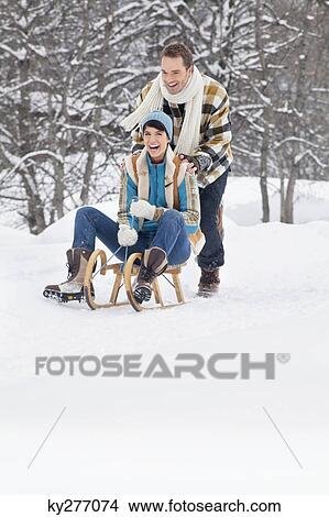 Picture - Young man pushing woman on sled. Fotosearch