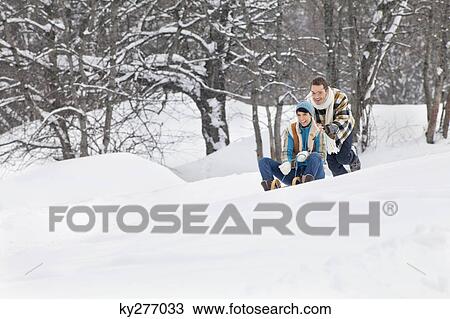 Young man pushing woman on sled View Large Photo Image Stock Image - Young man pushing woman on sled. Fotosearch