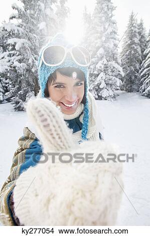 Picture - Young woman in winter clothes giving thumbs up sign. Fotosearch