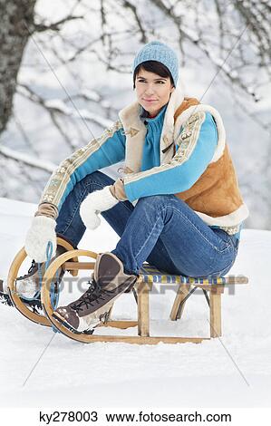 Young woman sitting on sled View Large Photo Image Stock Image - Young woman sitting on sled. Fotosearch