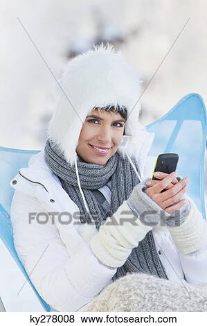 Young woman using mobile phone in snow View Large Photo Image Stock Photo - Young woman using mobile phone in snow. Fotosearch