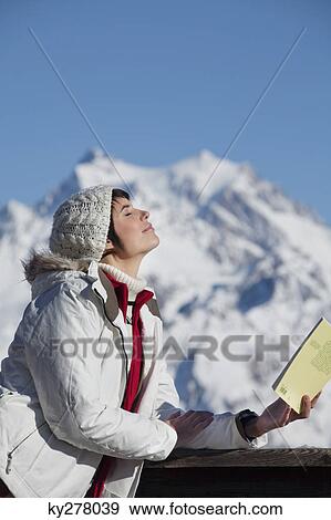 Young woman with book, enjoying winter sun, mountains in background View Large Photo Image Stock Photo - Young woman with book, enjoying winter sun, mountains in background. Fotosearch