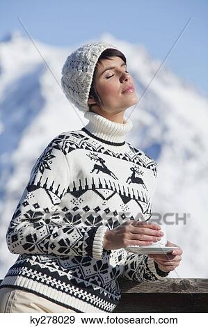 Young woman with coffee cup, enjoying winter sun, mountains in background View Large Photo Image Stock Photo - Young woman with coffee cup, enjoying winter sun, mountains in background. Fotosearch