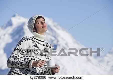 Young woman with coffee cup, enjoying winter sun, mountains in background View Large Photo Image Stock Photograph - Young woman with coffee cup, enjoying winter sun, mountains in background. Fotosearch