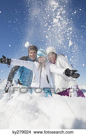 Couple and daughter in ski wear, throwing snow in air View Large Photo Image Picture - Couple and daughter in ski wear, throwing snow in air. Fotosearch