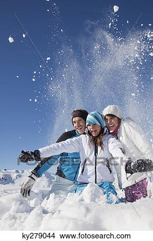Picture - Couple and daughter in ski wear, throwing snow in air. Fotosearch