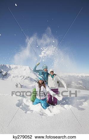 Stock Image - Couple and daughter in ski wear, throwing snow in air. Fotosearch