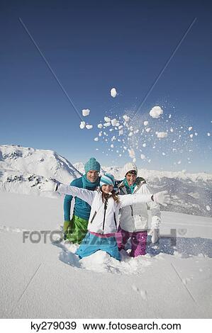 Stock Photo - Couple and daughter in ski wear, throwing snow in air. Fotosearch