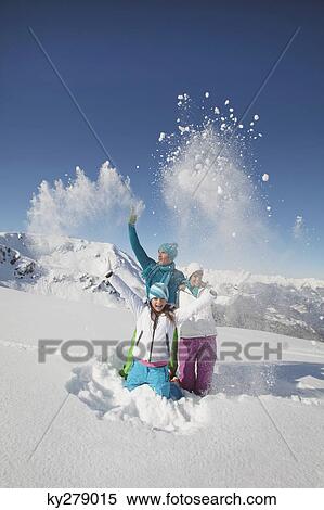 Stock Photography - Couple and daughter in ski wear, throwing snow in air. Fotosearch