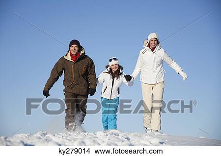 Picture - Couple and daughter in ski wear walking in snow. Fotosearch