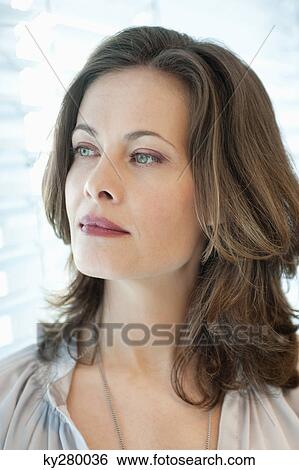 Close-up of a woman looking out of a window View Large Photo Image Stock Photograph - Close-up of a woman looking out of a window. Fotosearch