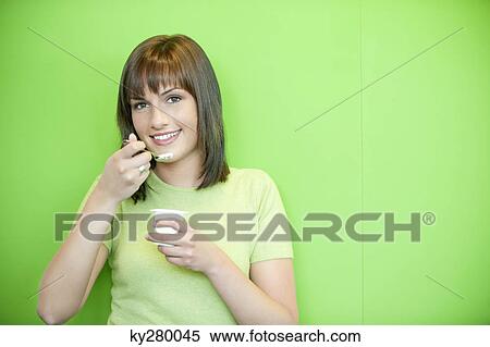 Stock Photography - Portrait of a woman eating yogurt. Fotosearch