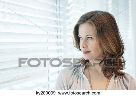 Woman looking out of a window View Large Photo Image Stock Photo - Woman looking out of a window. Fotosearch