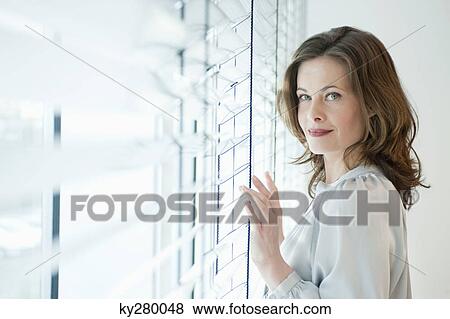 Woman touching a window and smiling View Large Photo Image Stock Photo - Woman touching a window and smiling. Fotosearch