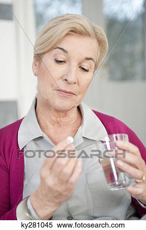 Stock Photography - Close-up of a woman taking a capsule. Fotosearch