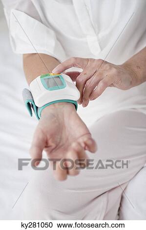 Stock Image - Woman checking her blood pressure. Fotosearch