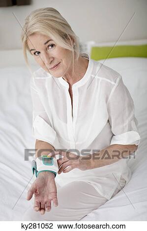 Woman checking her blood pressure View Large Photo Image Stock Image - Woman checking her blood pressure. Fotosearch
