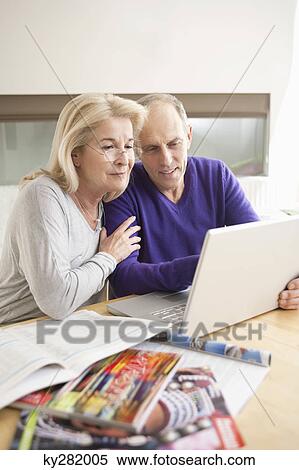 Couple looking at a laptop and smiling View Large Photo Image Stock Photography - Couple looking at a laptop and smiling. Fotosearch