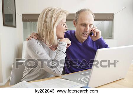 Stock Image - Couple sitting together in front of a laptop. Fotosearch